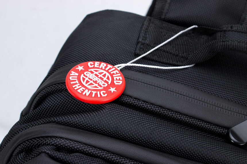Black backpack with a red 'Certified Authentic' tag on a light gray background