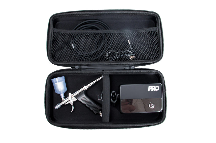 Open black travel case with airbrush and power adapter on a white background