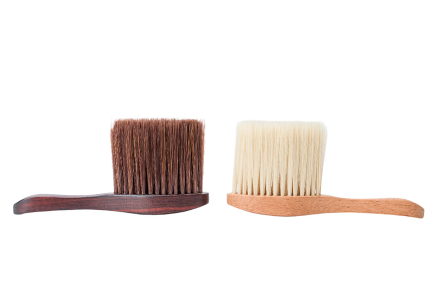 Two brushes, one with brown bristles and wooden handle, the other with white bristles and wooden handle, on a white background.