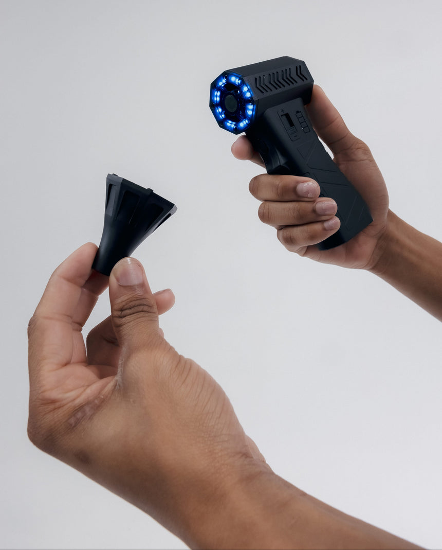 Two hands holding a futuristic black device with a glowing blue circle on a white background