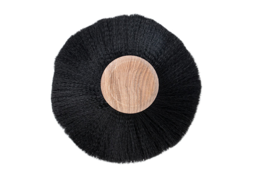 Black circular mat with a wooden center on a white background