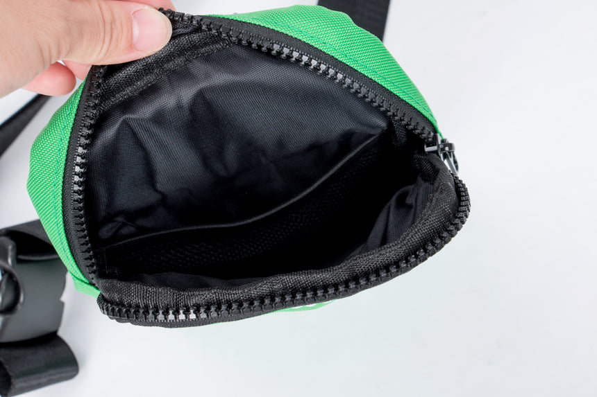 Green and black waist bag with a zipper on a white background