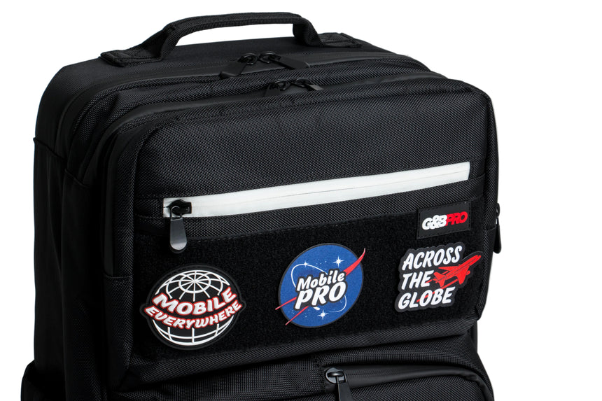 Black backpack with various patches on a gray background