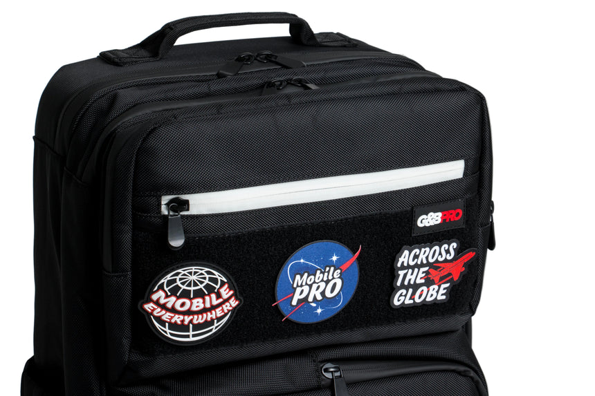 Black backpack with various patches on a gray background