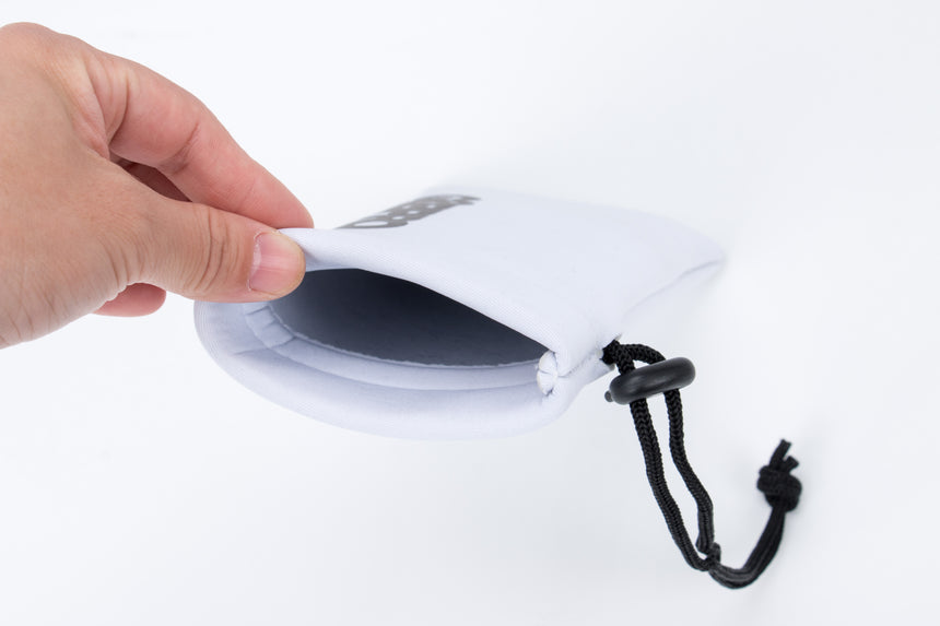 White drawstring pouch with a brand logo held by a hand on a white background