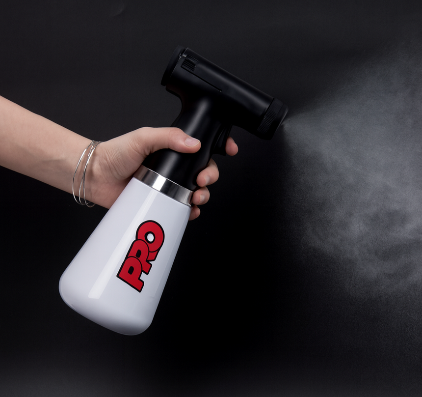 Hand holding a white and black vacuum cleaner with 'PRO' branding on a dark background
