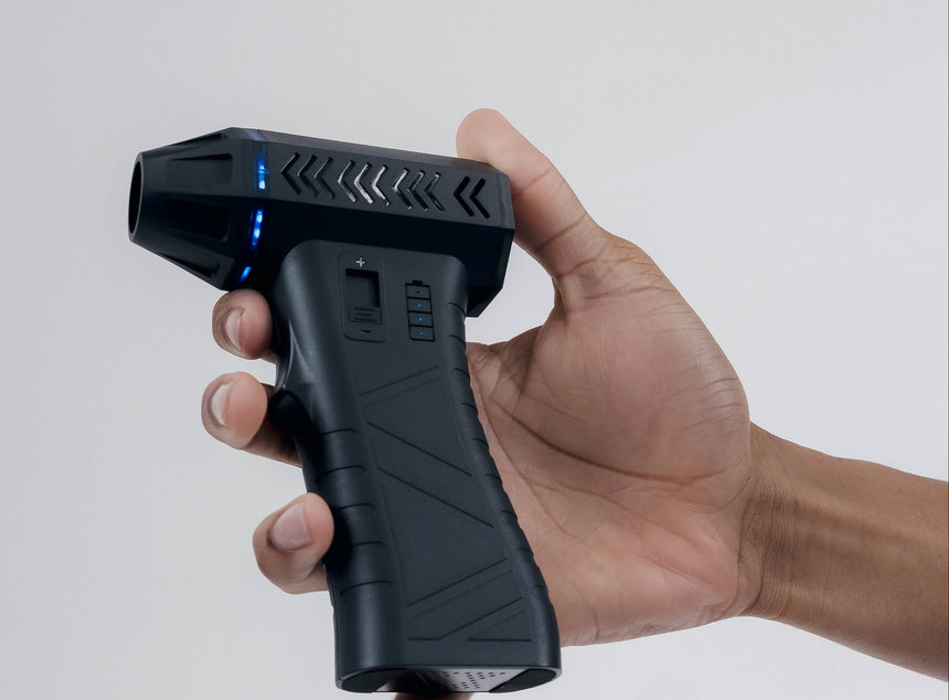 Hand holding a black handheld device against a white background