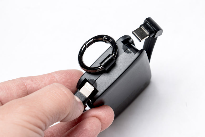 Black electronic device with a USB connector held by a hand on a white background