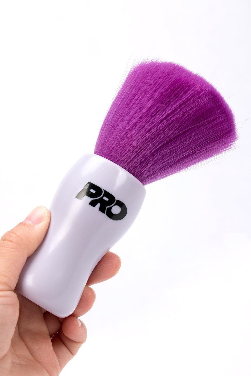 White brush with purple bristles held by a hand on a white background